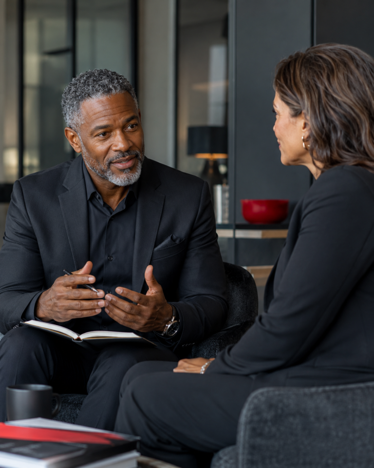Executive coach guiding a professional through a focused leadership conversation