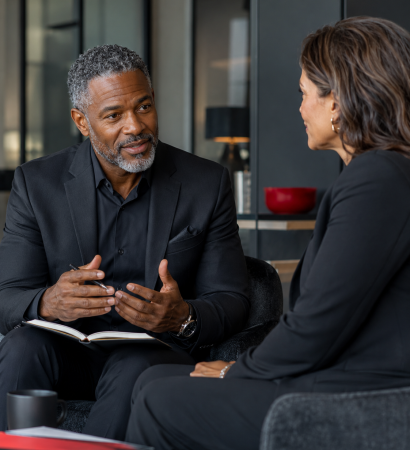 Executive coach guiding a professional through a focused leadership conversation